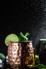 Moscow mule cocktail with lime, ginger beer, vodka and mint garnish. splashes and ice frozen...