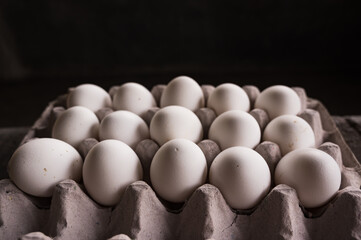 The Chickens eggs on the egg carton on the dark background in natural light

