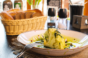 Roasted cauliflower with cream sauce and pesto. Old white plate with broun cloth. Delicious...