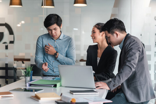 Group Of Asian Businessman And Businesswoman Brainstorm For Collaborative Planning Using Laptop And Documents At The Office.