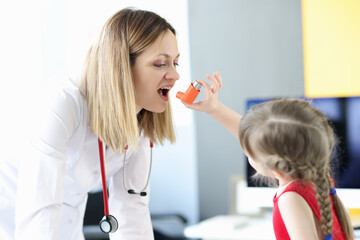 Little girl spraying hormonal inhaler to doctor in clinic