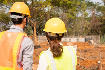 A team of male and female engineers or architects is exploring and inspecting the outdoor construction site work