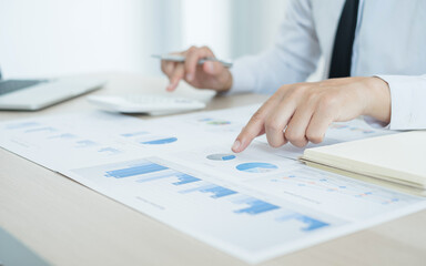 The businessman hand sits at their desks and calculates financial graphs showing the results of their investments planning the process of successful business growth