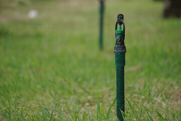 Automatic sprinkler system watering the lawn on a background of green grass in Thailand.
