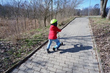 little boy rollerblading in a red jacket and yellow bicycle helmet in Budapest suburb, Hungary