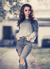 Happy young fashion woman in gray blue pullover and ripped jeans