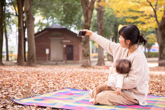 秋の公園で自撮りするママと赤ちゃん
