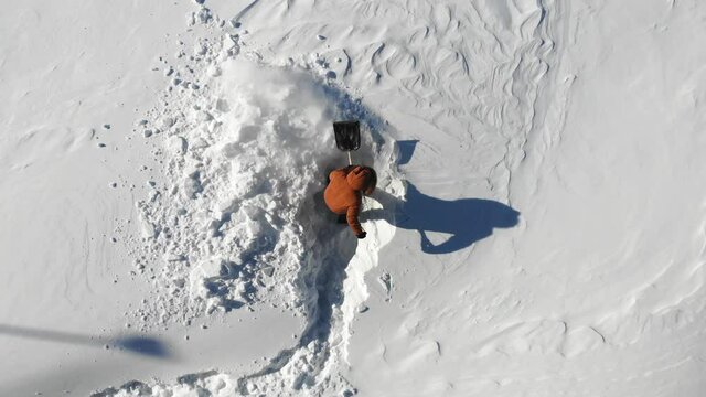 Aftermath of a blizzard. Man shovels snow in the yard in winter