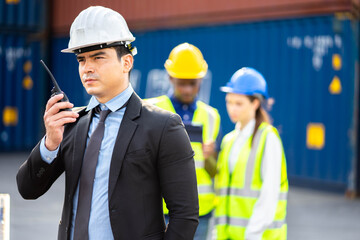 Builder Engineering in hardhat with radio communication over group of builders at construction site.