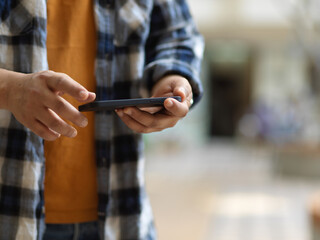 Obraz na płótnie Canvas A man using horizontal smartphone screen while standing in blurred background