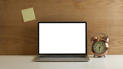 Workspace with mock up laptop, clock and sticky note on wooden wall