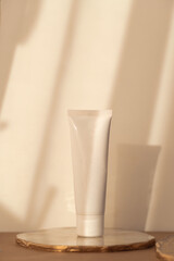 White cosmetic tube mockup on warm soft light background. Minimalism product still life. Light and...
