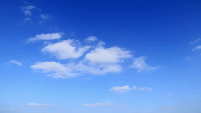 Fluffy white clouds floating in blue sky, time-lapse