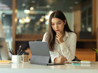 Portrait of female office worker working digital tablet on office desk