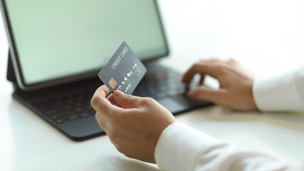 Close up view of hand holding credit card and typing on tablet keyboard for online payment