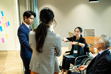 車椅子の女性社員が意見を話している