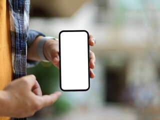 Male hand holding smartphone to show mock up screen to camera on blurred background
