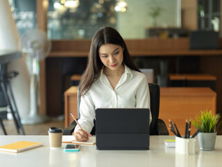 Businesswoman focusing on her work with digital tablet on office desk