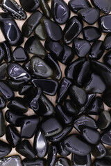 Gold obsidian jewel heap on light wood texture. Pile mineral pebbles background.