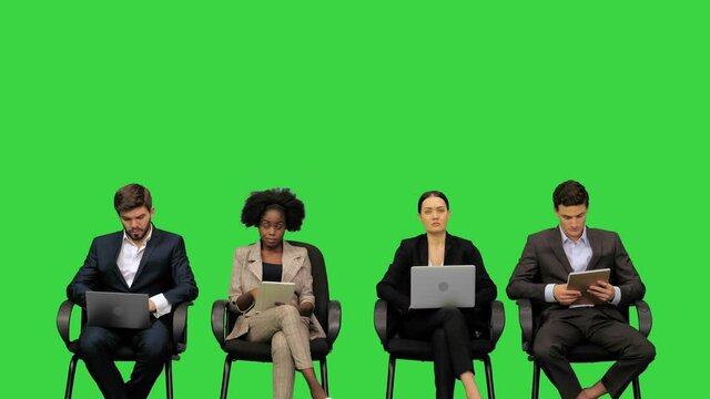 Business people at the presentation taking notes on their laptops, listening attentively, asking questions on a Green Screen, Chroma Key.