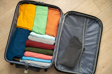 Top view of an open suitcase prepared for travel. Neatly folded clothing for the vacation trip. Excited state before the trip.