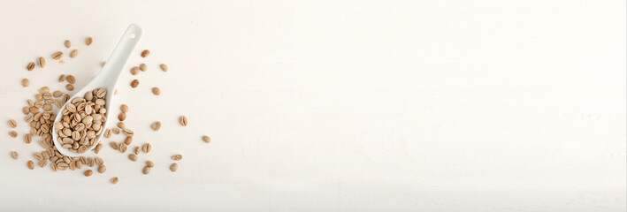 Spoon of coffee beans on light background with space for text