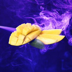 Fresh mango and color smoke on dark background