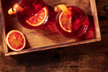 Negroni cocktail with blood oranges, overhead shot on a wooden background