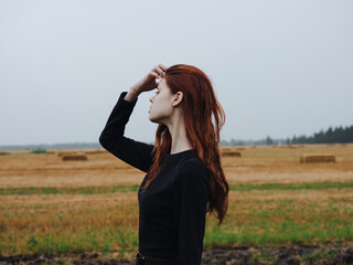 A beautiful woman in a black dress walks in a field on nature in autumn