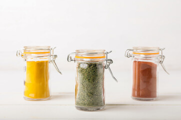 Jars with different spices on wooden table against white background