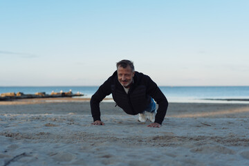 Active sporty man working out doing press-ups on a sandy beach