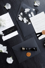Wedding invitation, trendy black background with flower petals. A set of dark wedding printing on a wooden background.
