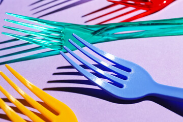 Plastic forks on color background