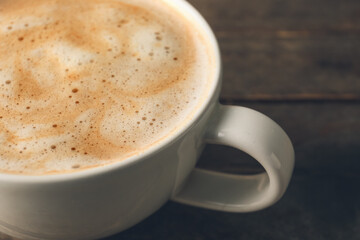 Cup of tasty latte on wooden background, closeup