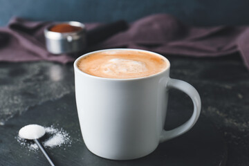 Cup of tasty latte on dark background