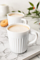 Cups of tasty latte on light background