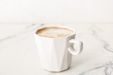 Cup of tasty latte on light background