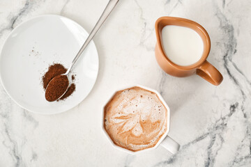 Composition with cup of tasty latte, coffee powder and pitcher with milk on light background