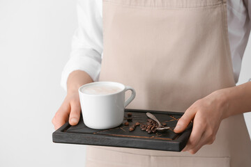 Woman holding tray with tasty latte on light background