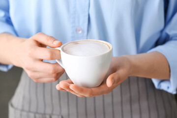 Woman holding cup of tasty latte, closeup