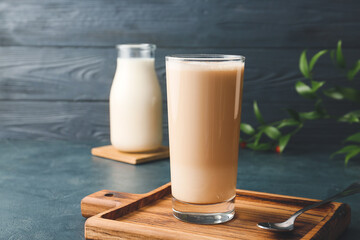 Glass of tasty latte on color wooden background