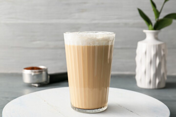 Glass of tasty latte on grey wooden background