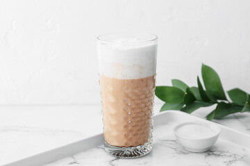 Glass of tasty latte on light background