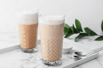 Glasses of tasty latte on light background