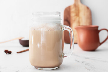 Mason jar of tasty latte on light background