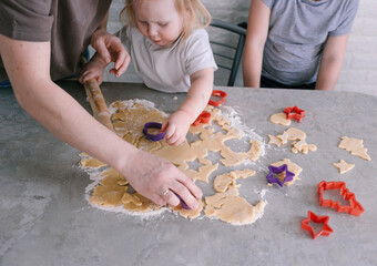 mom helps the children cut out beautiful cookie shapes from the dough. top view