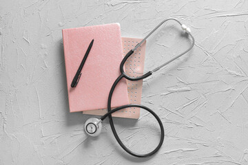 Modern stethoscope, notebooks and pen on grey background