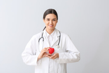 Cardiologist with red heart on light background