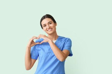 Cardiologist making heart with her hands on color background