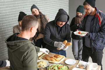 Volunteer giving food to homeless people in warming center